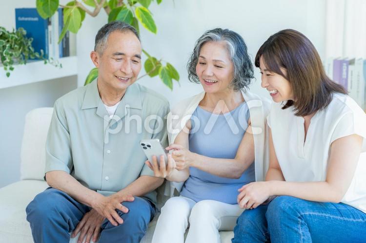 リビングでスマホを見るシニア夫婦と子供 シニア,夫婦,スマホの写真素材
