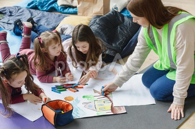 寝転ぶ女の子たちと一緒にお絵描きする女性 女性,女の子,人物の写真素材