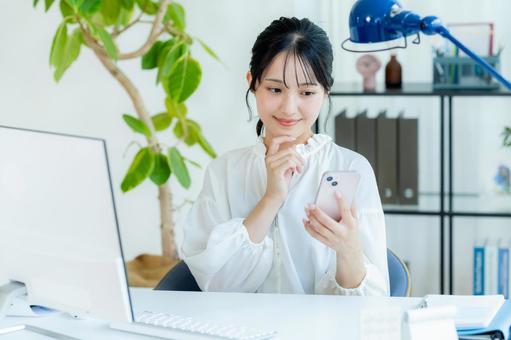 オフィスでスマホを持つビジネスウーマン スマホ,笑顔,ビジネスウーマンの写真素材