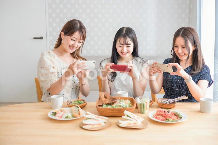 スマホで料理写真を撮る女性たち 料理,写真,撮るの写真素材