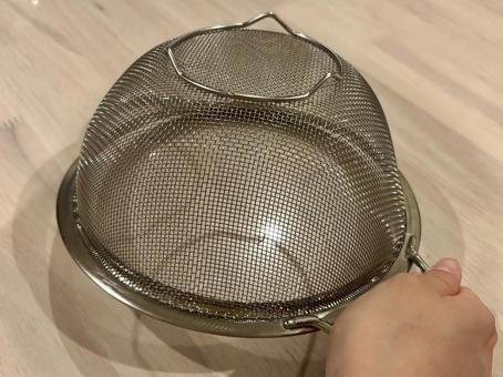 逆さになった銀の水切りを持つ 逆さになった銀の水切りを持つ ザル,ステンレス,水切りの写真素材