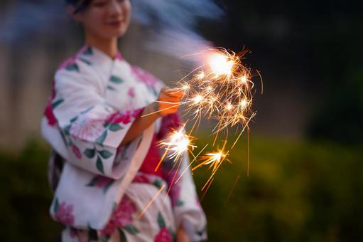 浴衣姿の女性が花火を持って立つ 花火,手元ち花火,煙の写真素材