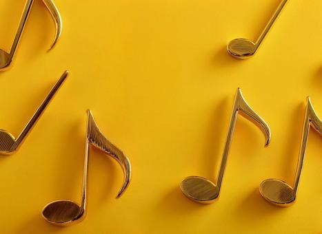 黄色の背景に飾られた金属製の音符 黄色の背景に飾られた金属製の音符の写真