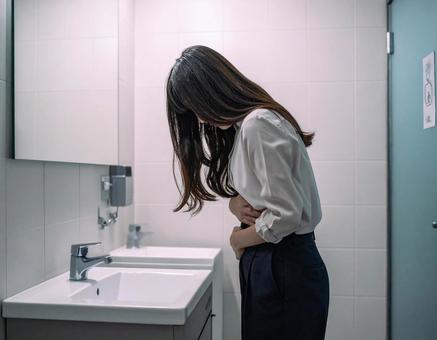 トイレでお腹を痛める女性 トイレでお腹を痛める女性の写真