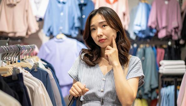 アパレルショップで悩むオシャレな女性  アパレルショップで悩むオシャレな女性 の写真