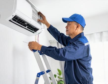 エアコン室内機を修理するベテラン技術者 エアコン室内機を修理するベテラン技術者の写真