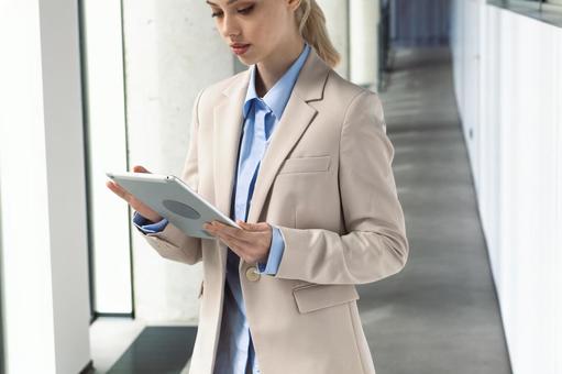 オフィスの通路でタブレットを使っているビジネスウーマン ビジネスウーマン,ビジネス,女性の写真素材