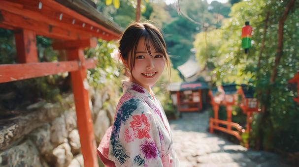 神社の境内にいる浴衣姿の若い女性の写真