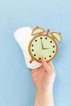 生理用ナプキンと紙でできた時計を持つ手 生理,月経,手の写真素材