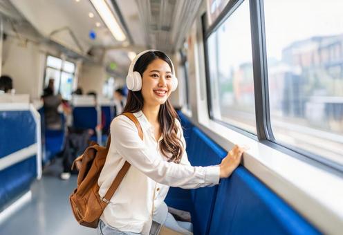 ヘッドフォンをつけて電車に乗っている女性 ヘッドフォンをつけて電車に乗っている女性の写真