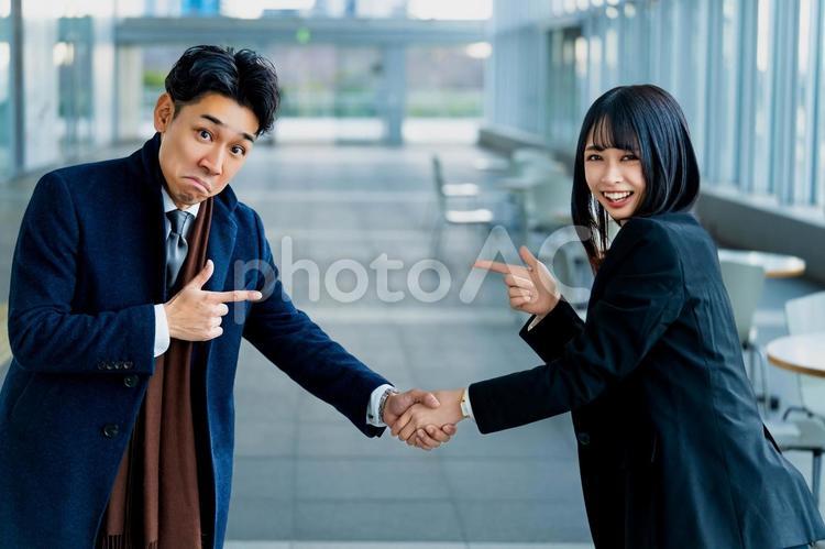 握手をしながらお互い指差すビジネス系男女 ビジネスウーマン,ビジネスマン,女性の写真素材