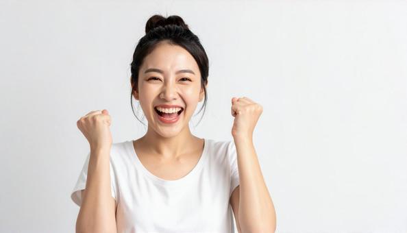 両手を上げて喜ぶ笑顔の若いアジア人女性の写真