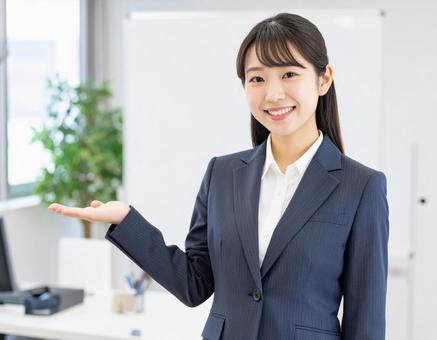 スーツ姿でオフィスを案内する女性 スーツ姿でオフィスを案内する女性の写真