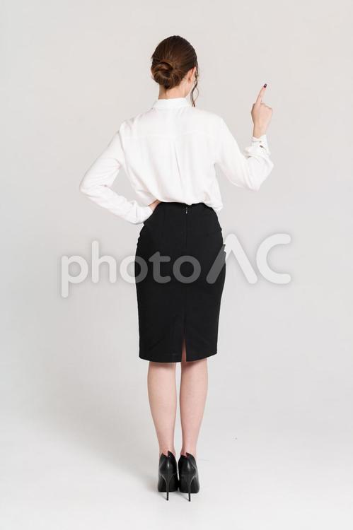 左腰に手を当て指差しする女性の後ろ姿 後ろ姿,腰に手,1番の写真素材