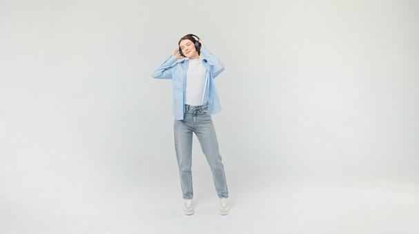 目を瞑りヘッドホンで聴いている女性 目を瞑りヘッドホンで聴いている女性の写真