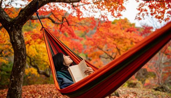 ハンモックで毛布に包まり読書する女性 ハンモックで毛布に包まり読書する女性の写真