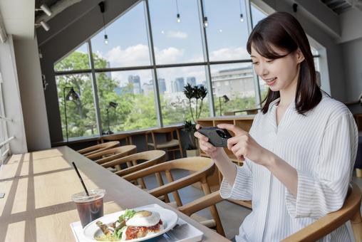 カフェでスマホを使う女性 カフェでスマホを使う女性の写真