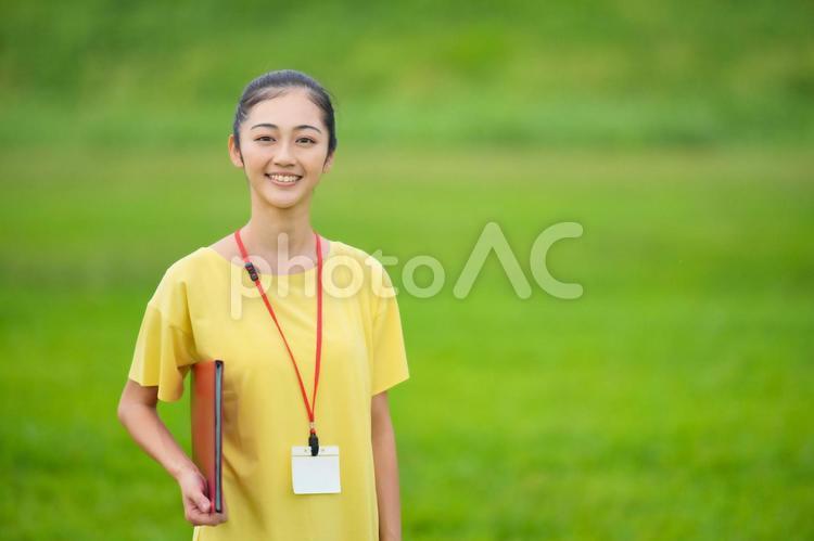 赤いファイルを持ってカメラ目線の女性（正面） 女性,インストラクター,資料の写真素材