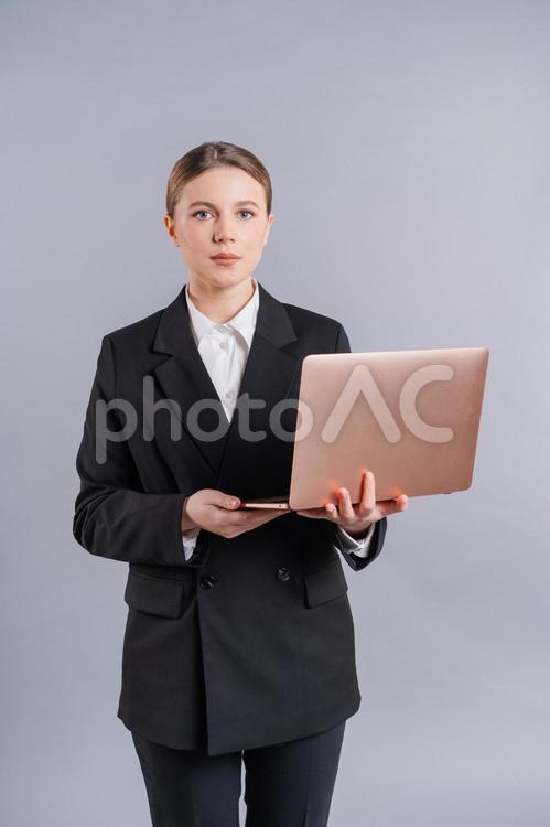 両手でノートパソコンを持ち立つ女性 女性,ノートパソコン,持つの写真素材