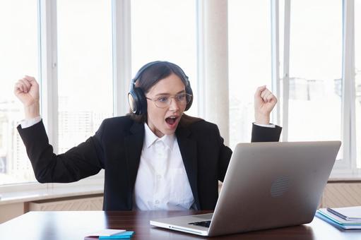 窓際の席でガッツポーズでパソコンを見る女性 女性,外国人,ガッツポーズの写真素材