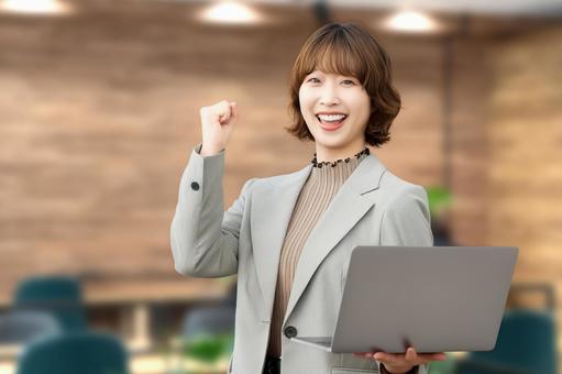 パソコンを持ってガッツポーズをする女性 女性,ビジネス,笑顔の写真素材