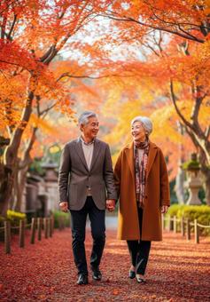 手をつなぎ紅葉道を散策するシニアカップル 手をつなぎ紅葉道を散策するシニアカップルの写真