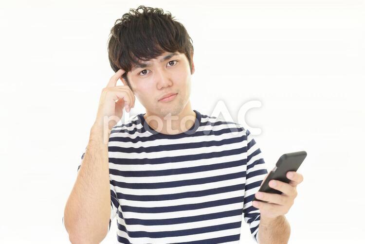 困惑した表情の男性 男性,男,スマートフォンの写真素材