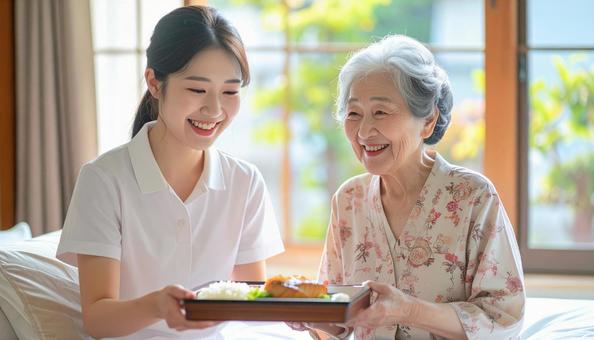 高齢女性と女性介護士の穏やかな食事風景 高齢女性と女性介護士の穏やかな食事風景の写真