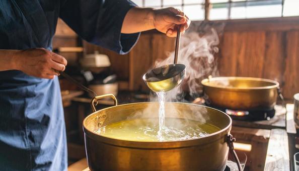 だし汁をおたまで鍋に注ぐ だし汁をおたまで鍋に注ぐの写真