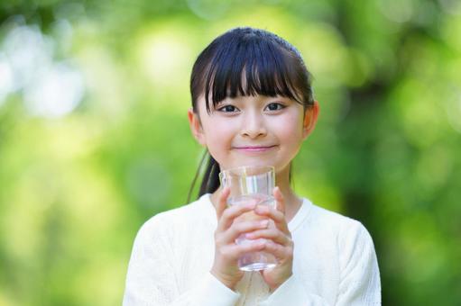 公園でグラスに入った水を持っている笑顔の女の子 子ども,女の子,小学生の写真素材