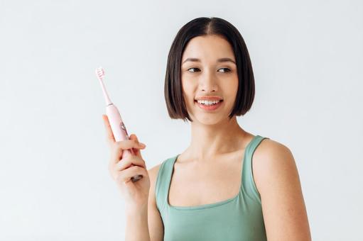 電動歯ブラシを持っている女性 電動歯ブラシを持っている女性の写真