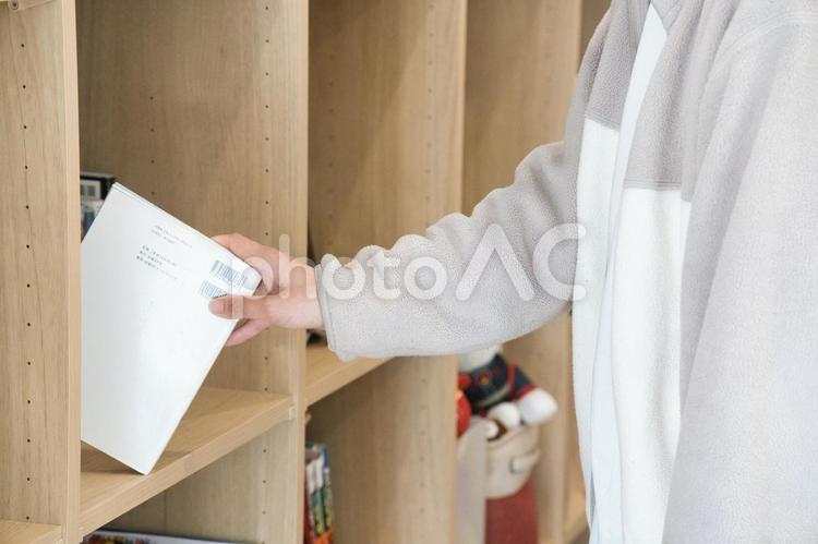 自宅の本棚から本を選び取る女性 読書,本,本棚の写真素材
