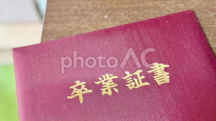 テーブルに置いた赤い表紙の卒業証書 卒業証書,大学,高校の写真素材