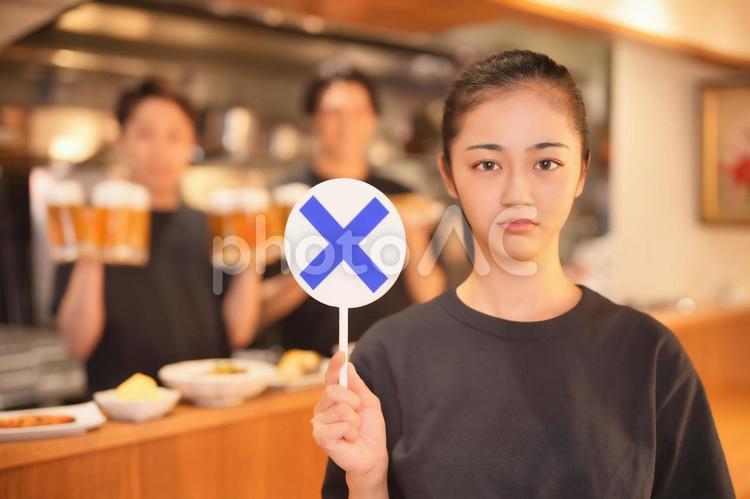 カウンターでバツの札を持つ女性 男女,大学生,〇×クイズの写真素材