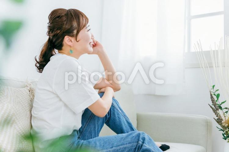 ソファでくつろぐ笑顔の日本人女性の横顔 女性,横顔,幸せの写真素材