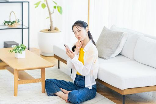 スマホを持って考える若い女性 スマホ,困る,悩むの写真素材