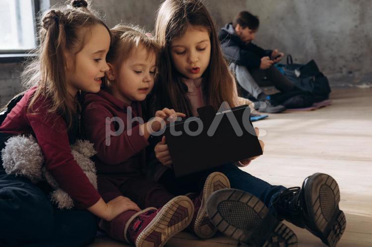 タブレットを見る女の子と後ろに男性 女の子,人物,貧困の写真素材