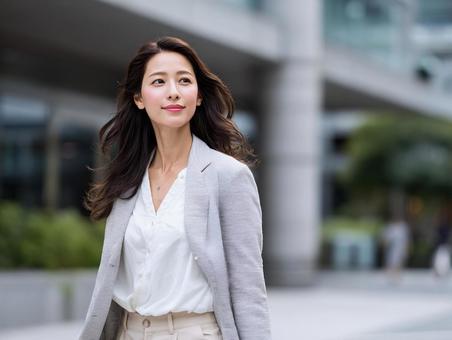 オフィス街を歩くビジネスウーマン オフィス街を歩くビジネスウーマンの写真