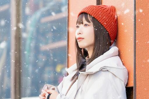 雪の降る冬の街角に立つ笑顔の女性 冬,雪,女性の写真素材