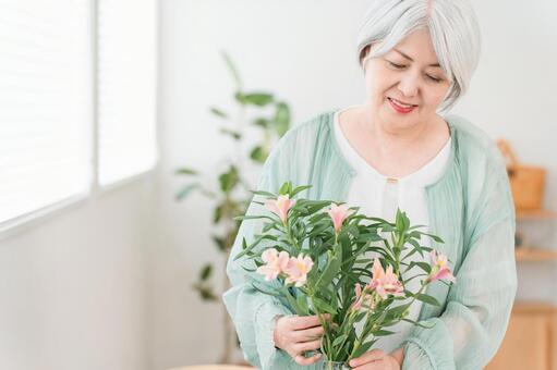 自宅のリビングで花を生けるシニア女性 シニア,花瓶,花の写真素材