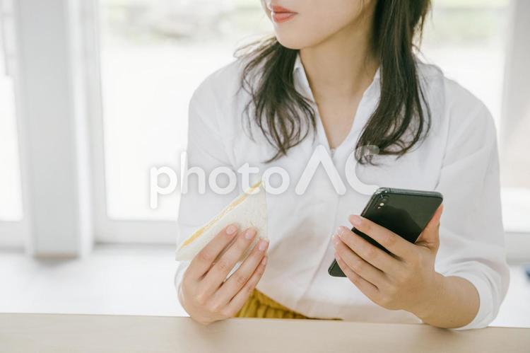 朝食をとる女性　サンドウィッチをもつ女性 料理,白,グレーの写真素材