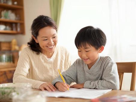 リビングで子どもの勉強を見るママ リビングで子どもの勉強を見るママの写真