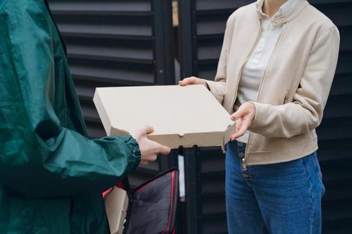 女性にピザを渡す配達員の男性 配達,フードデリバリー,デリバリーの写真素材