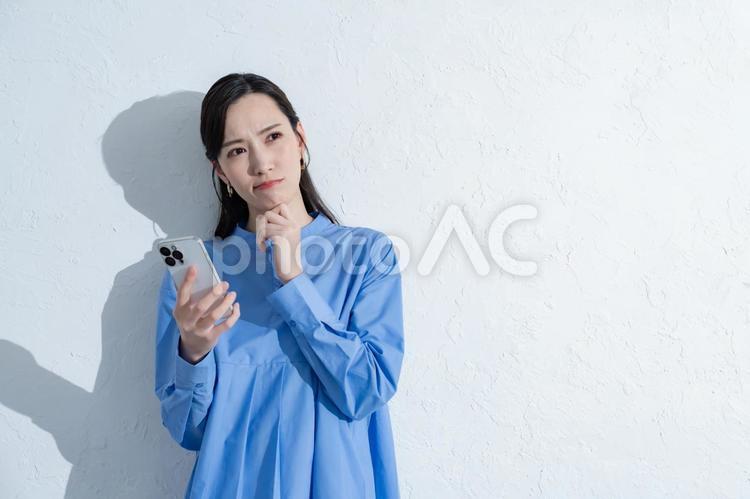 携帯を持つ青いワンピースを着た女性 スマートフォン,スマホ,女性の写真素材