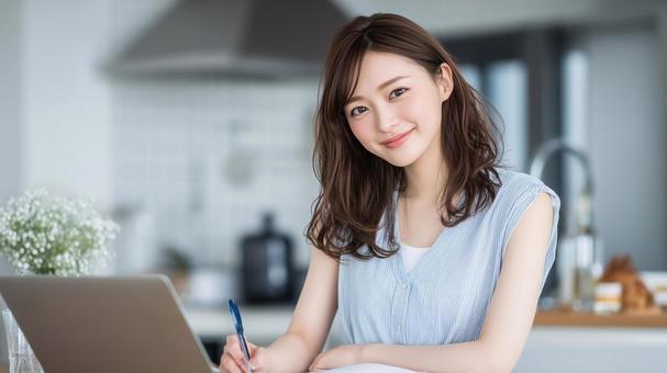 ノートPCでレシピを調べメモしている女性 ノートPCでレシピを調べメモしている女性の写真