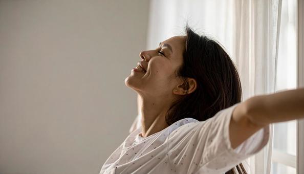 起床時に伸びをする白いパジャマの若い女性 起床時に伸びをする白いパジャマの若い女性の写真