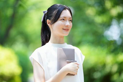 公園で女性が本を片手に持つ 女性,本,手帳の写真素材