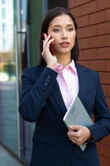 オフィスビルの外で電話しているビジネスウーマン ビジネスウーマン,ビジネス,女性の写真素材