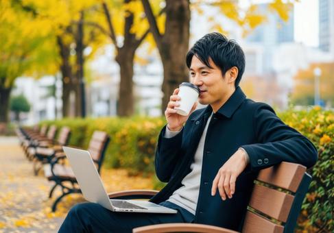 秋の公園でリモートワークする男性 秋の公園でリモートワークする男性の写真