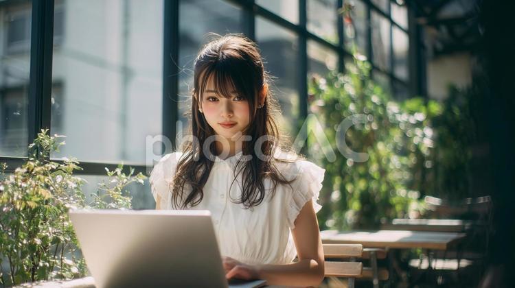 緑豊かなカフェでノートPCを使用する女性 カフェ,女性,緑の写真素材